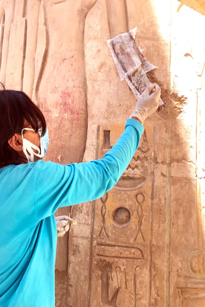 Eine Frau restauriert eine Säule des Karnak-Tempels, auf der Hieroglyphen zu sehen sind.