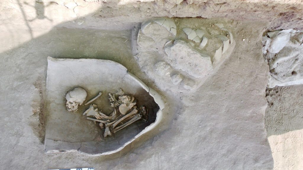 Freigelegtes Grab eines Kindes bei Küllüoba. Die Beine sind eng an den Körper gezogen und erinnern an einen Fötus im Mutterleib, nur der Kopf ist leicht angehoben.