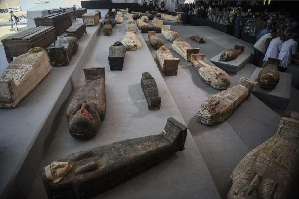 Das Bild zeigt eine Auswahl an Sarkophagen, die Mehrzahl aus Holz und in unterschiedlichen Größen, aus Sakkara. Einige der Sarkophage sind noch sehr gut erhalten und weisen noch die Reste der Bemalung auf.