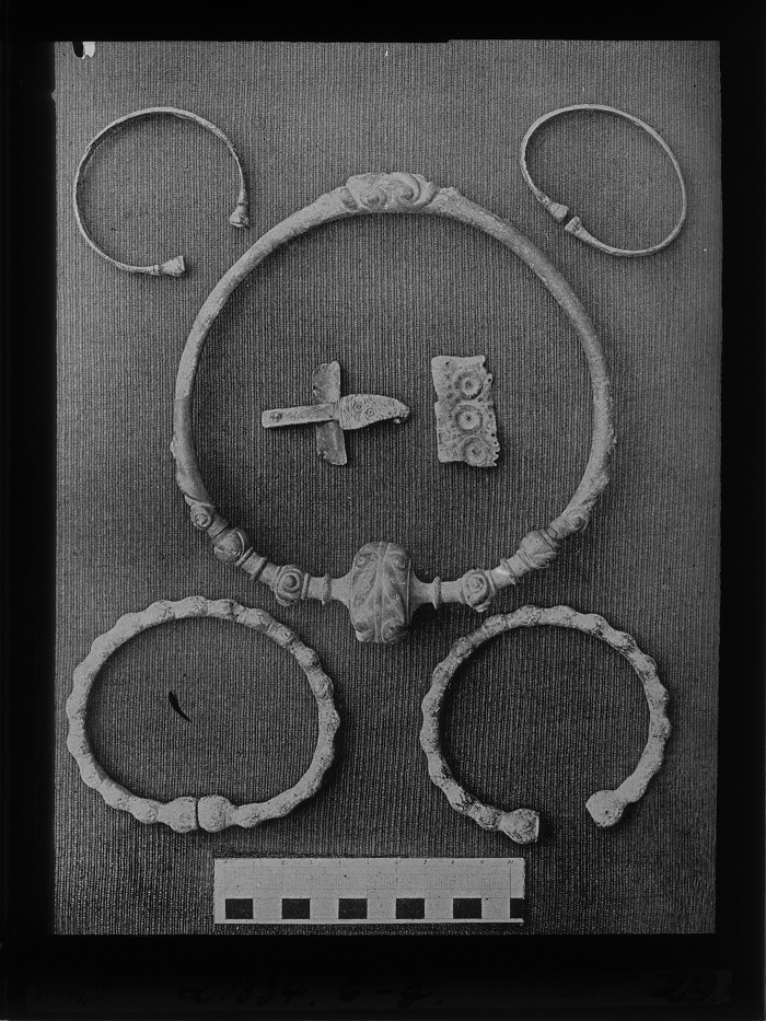 Fotoglasplatte (Teil der Archivbestände des Museums). Zu sehen ist ein Scan der Platte, auf der verschiedene Schmuckstücke liegen. Darunter zwei Armreifen, ein Halsreif und eine Fibel.