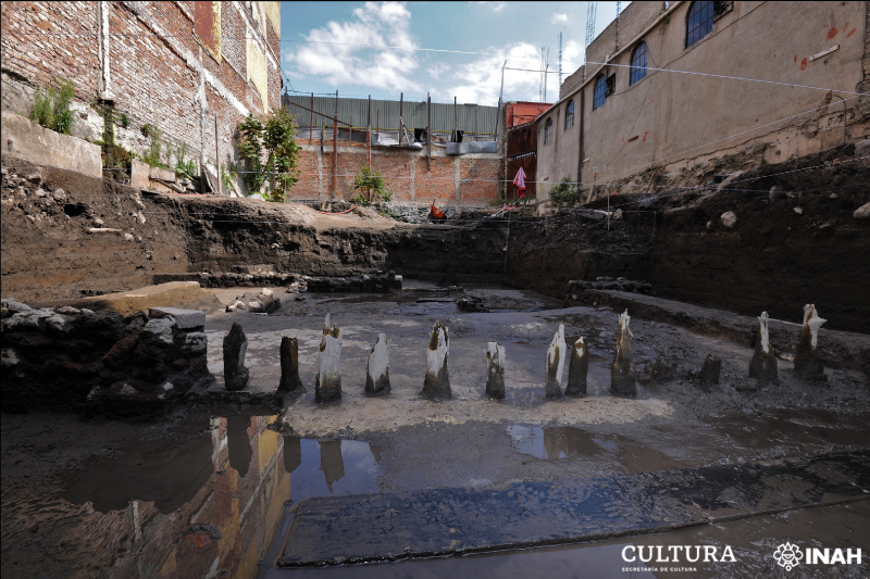 Das Bild zeigt den Grabungsschnitt on Mexiko-Stadt. Im Vordergrund sind die Überreste des Hauses, abgebrochene Holzpfähle zu sehen.