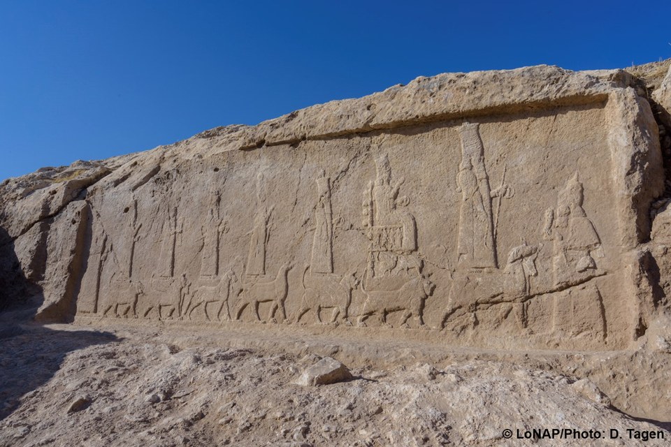 Felsrelief mit Darstellung einer Prozession. Acht Personen und acht Tiere stellen Götter dar, die auf ihren symbolischen Tieren stehen.