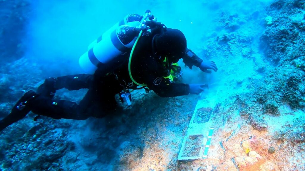 Ein Unterwasserarchäologe bei der Arbeit, untersucht einen Fund.