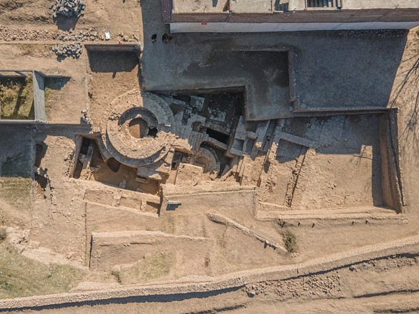 Die Luftbildaufnahme zeigt den Tempel von Gandhara. Zu sehen ist der Grabungsschnitt sowie freigelegte Mauerzüge in unterschiedlichen Tiefen, sodass die einzelnen Bauphasen des Tempels sichtbar sind.