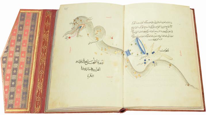 Die aufgeklappte Doppelseite aus dem Buch der Fixsterne zeigt eine schlangenartige Figur. Auf ihrem Körper stehen ein Kelch und ein weißer Vogel. Daneben befindet sich ein Text in arabischer Schrift und Sprache.