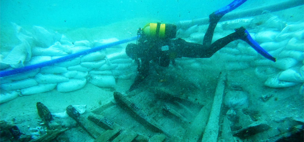 Archäologische Arbeiten am Schiffswrack von Ses Fontanelles. Aufgestapelte Sandsäcke sollen das gefährdete Schiff vor starken Wellen schützen.
