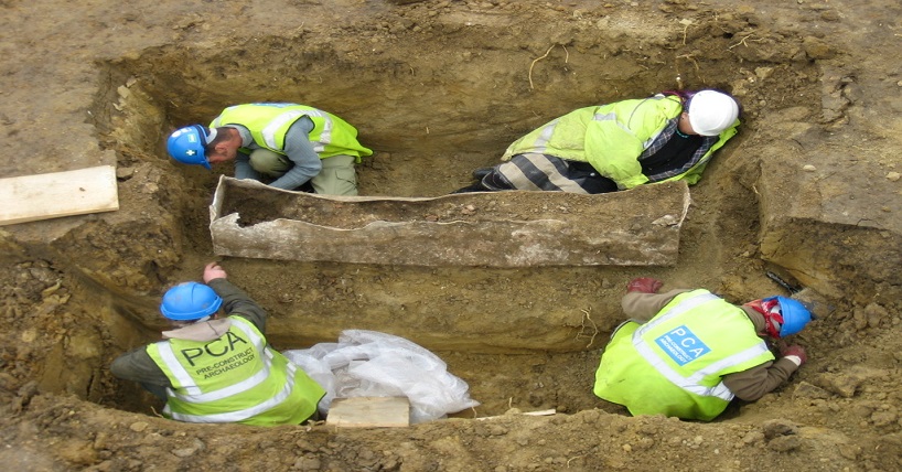Vier Archäologen legen den Sarkophag frei. Die Bleihülle ist noch sehr gut erhalten.