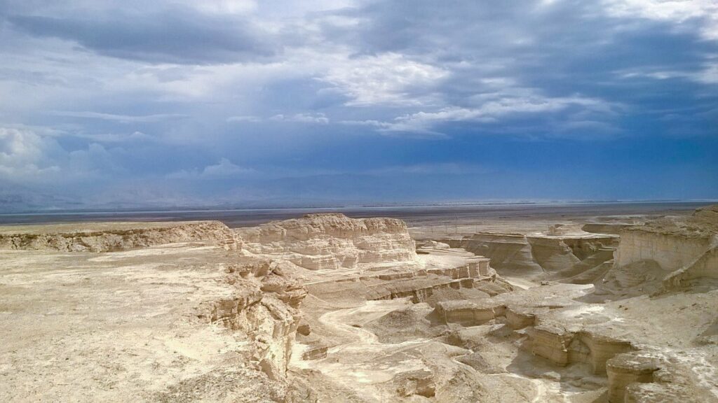 Blick von Masada über das Tote Meer: Die felsige Landschaft wird von einem tiefen Tal durchzogen. Im Hintergrund ist das Tote Meer zu sehen.
