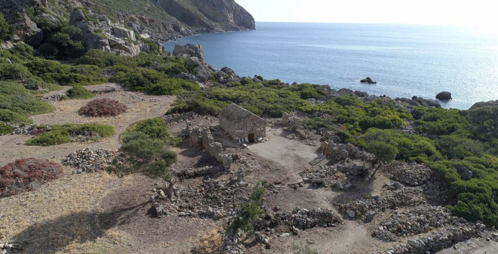 Ein einzelnes Gebäude umgeben von Mauerresten an der kretischen Küste