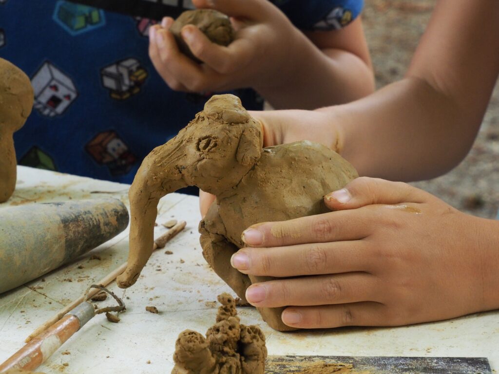 Historische Handwerkskurse für Kinder: zu sehen sind die Hände von zwei Kindern, die ein Mammut aus Ton formen.